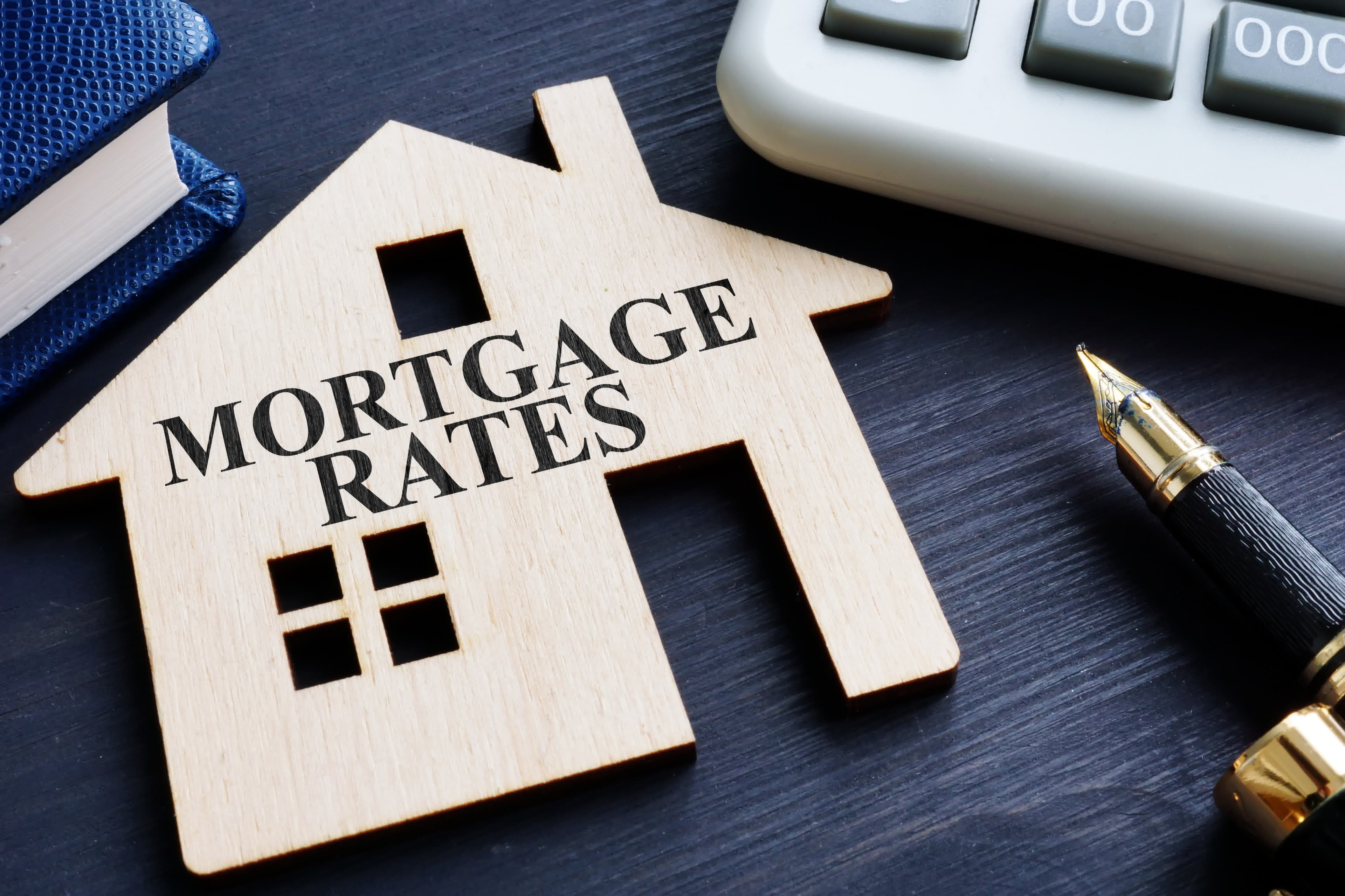 A wooden house cutout labeled mortgage rates beside a calculator, for ARM rates