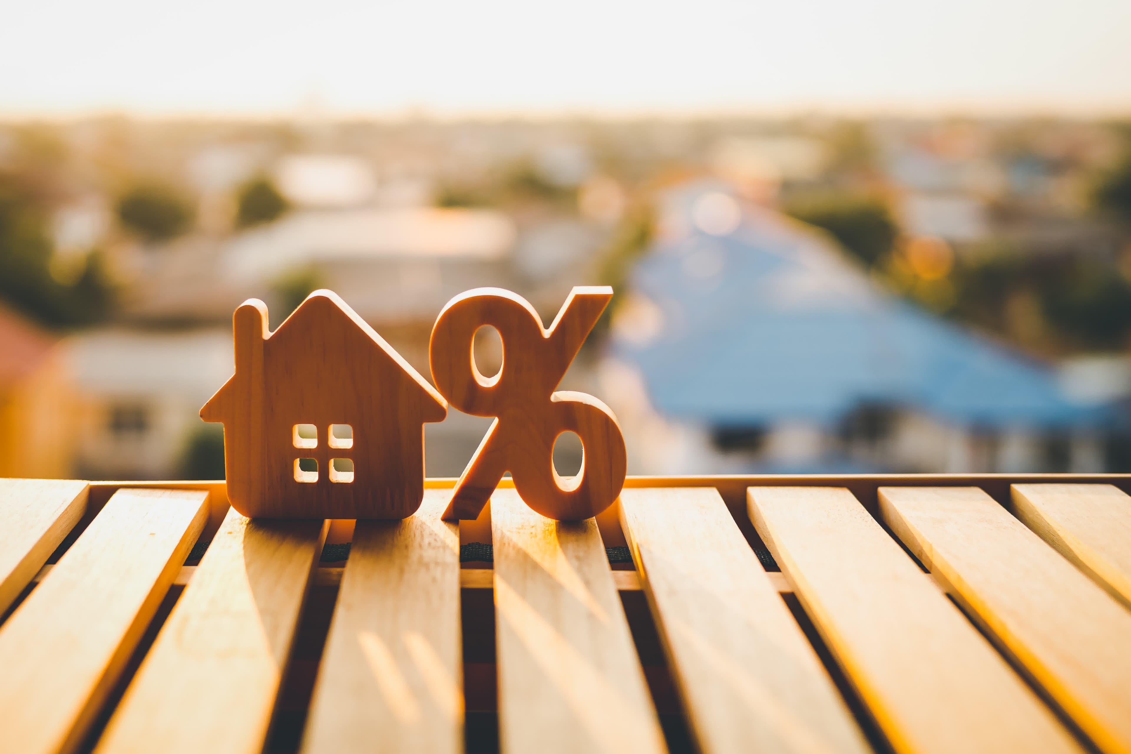 A model house beside a percent symbol representing a lower mortgage rate