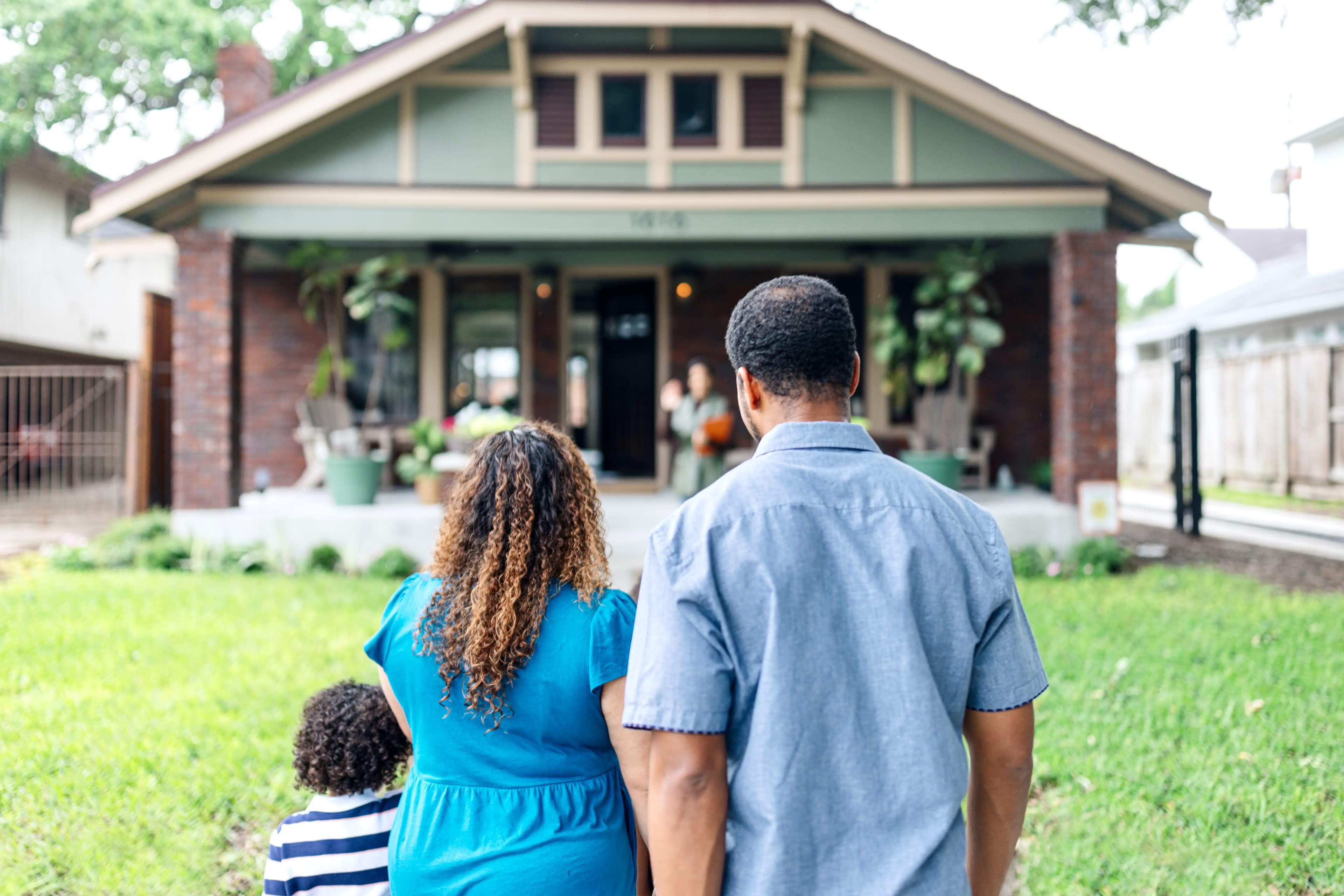 A young family walking toward their new Craftsman home financed with an FHA loan