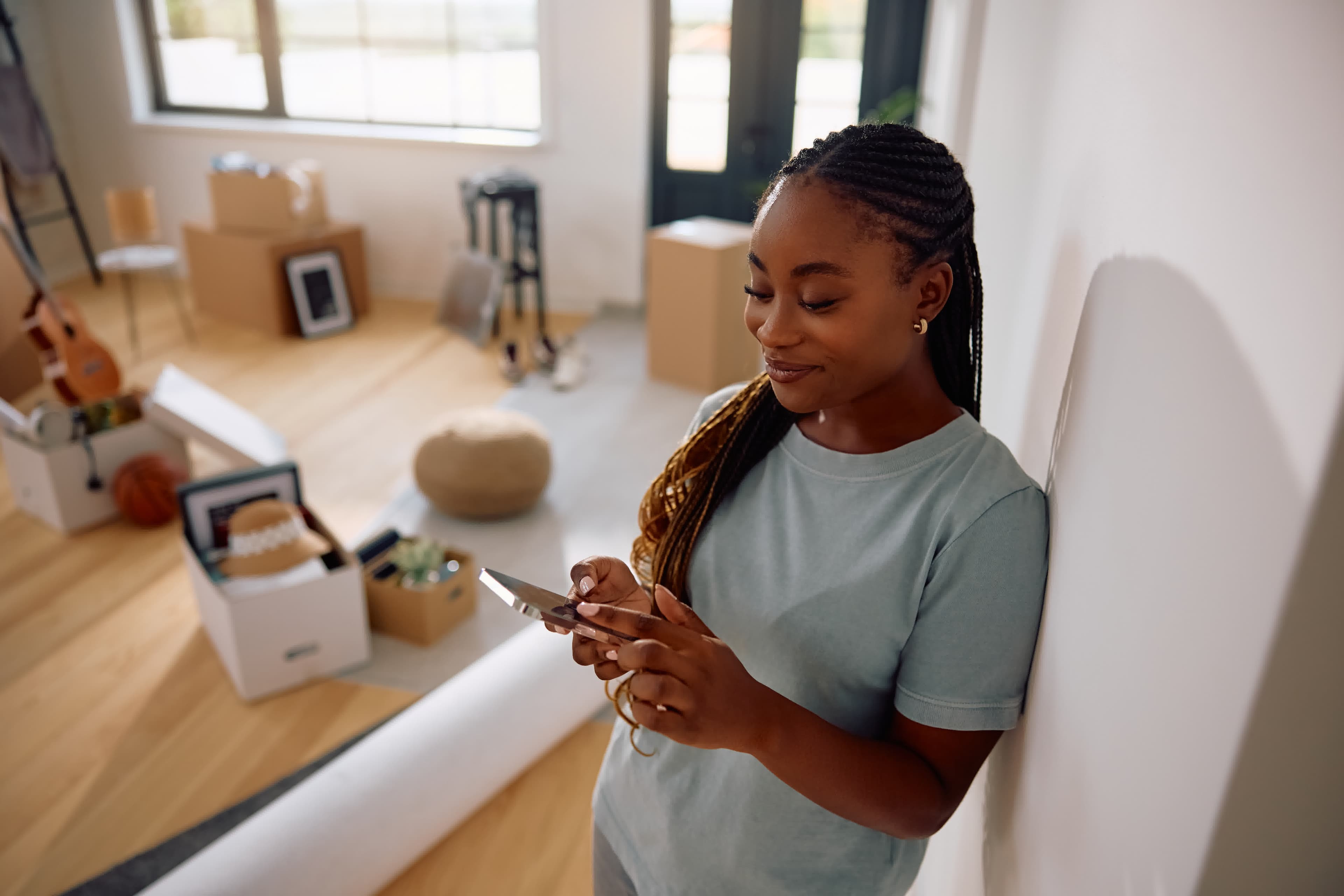 A self-employed California buyer using her phone among moving boxes in her new home