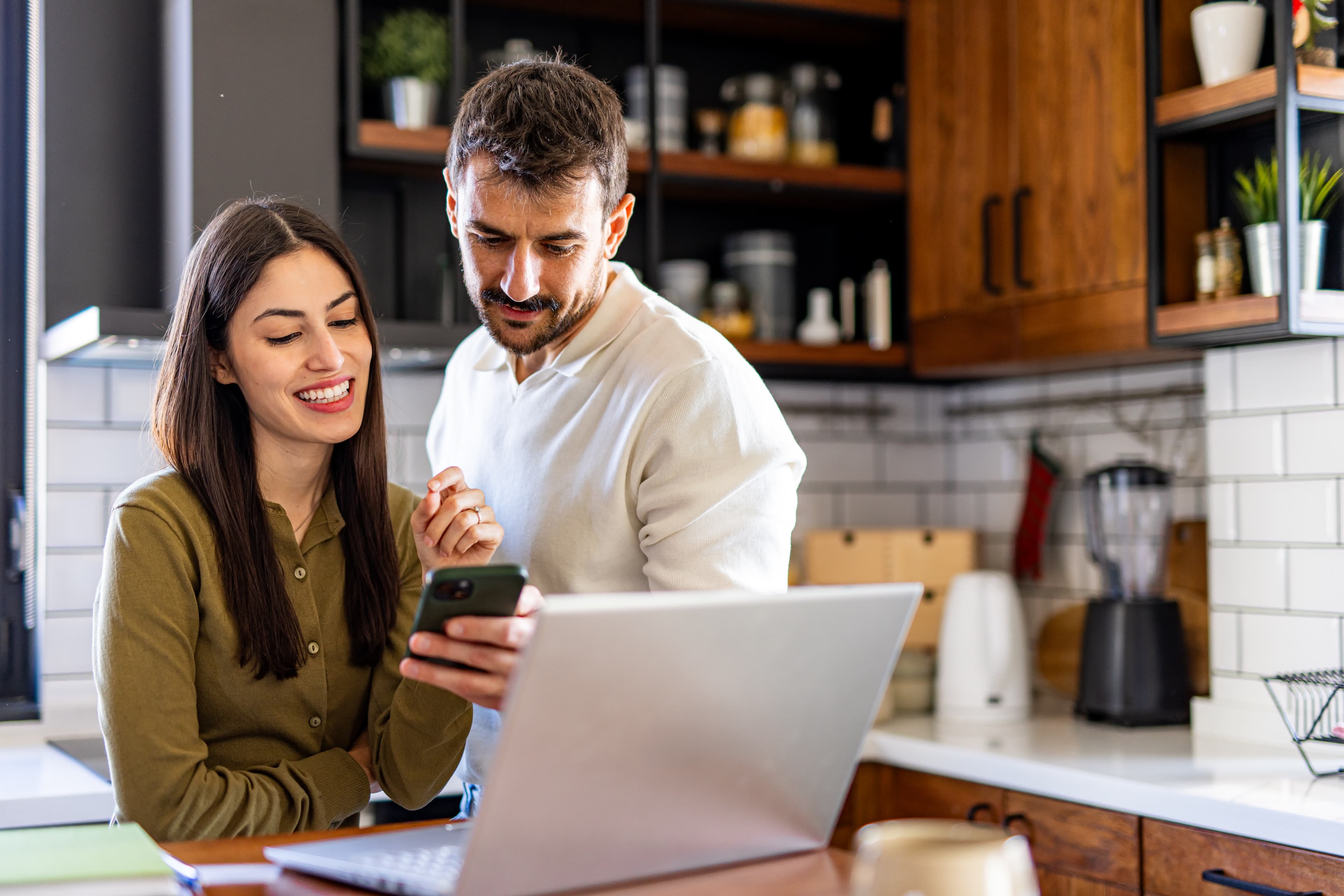 Couple uploading a mortgage statement on a phone and laptop for a fast refinance quote