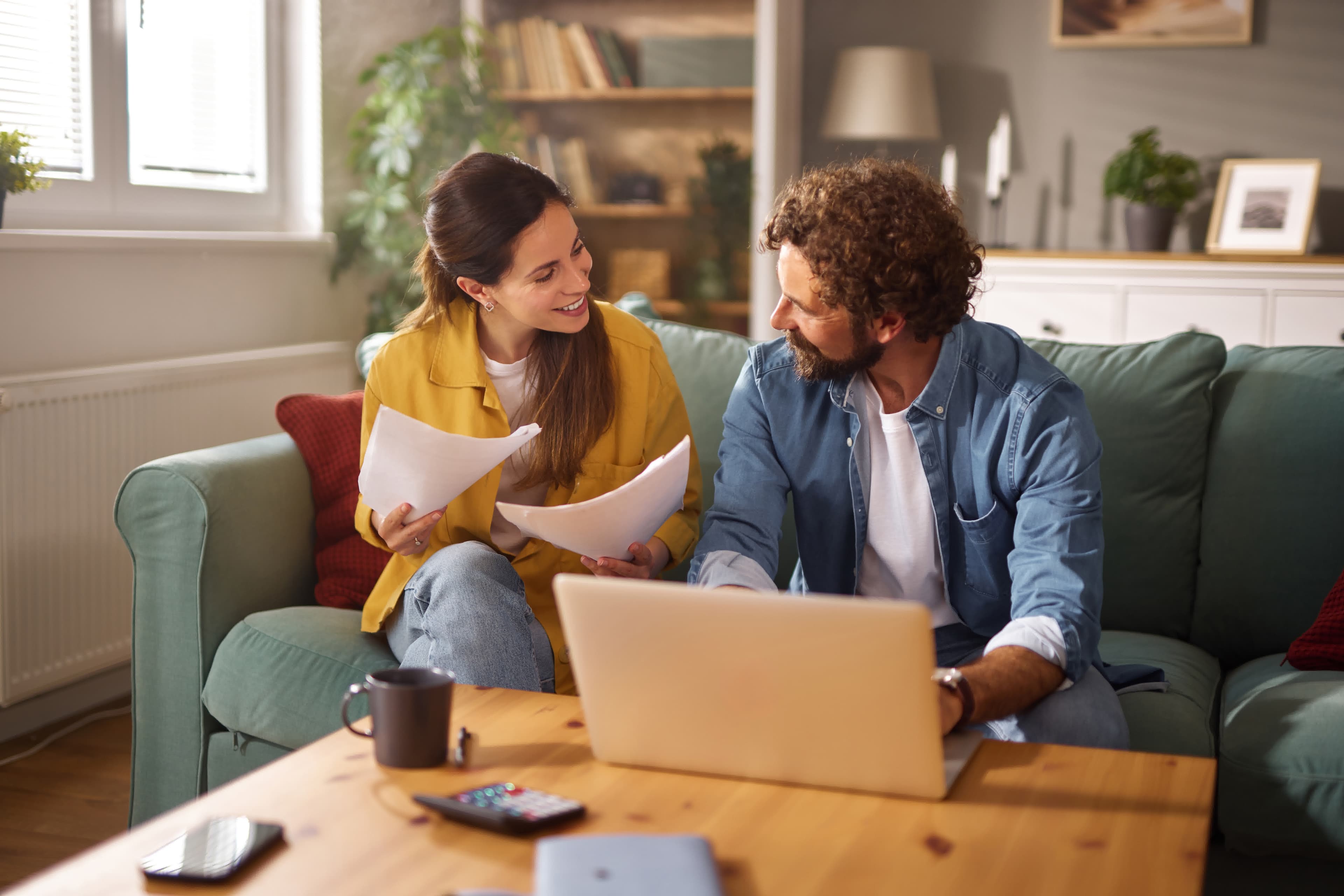 Couple reviewing refinance documents and a checklist on a laptop at home