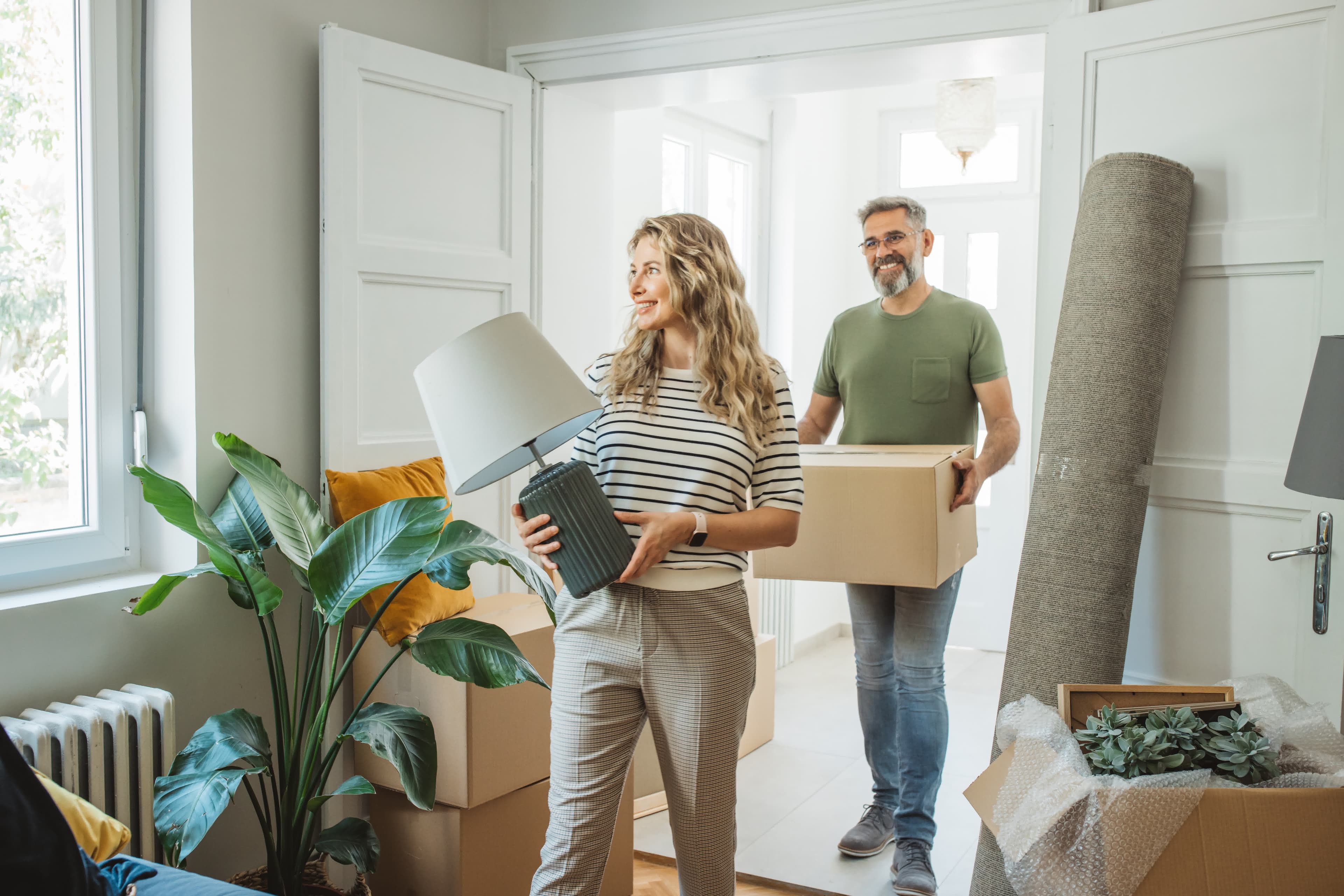 A couple moving boxes into a new home bought with a bridge loan before selling