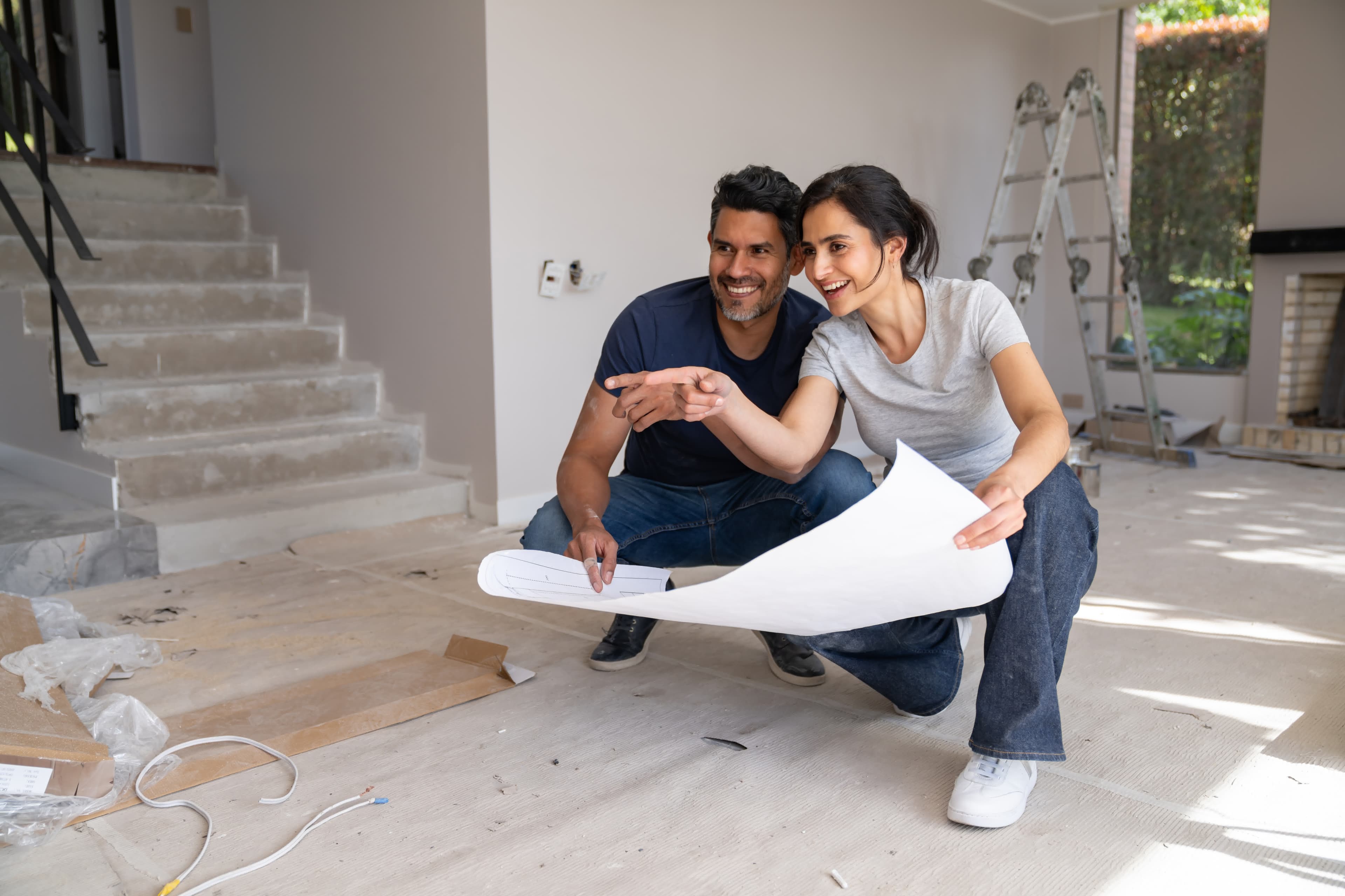 A couple reviewing blueprints in a home under renovation financed with a renovation loan
