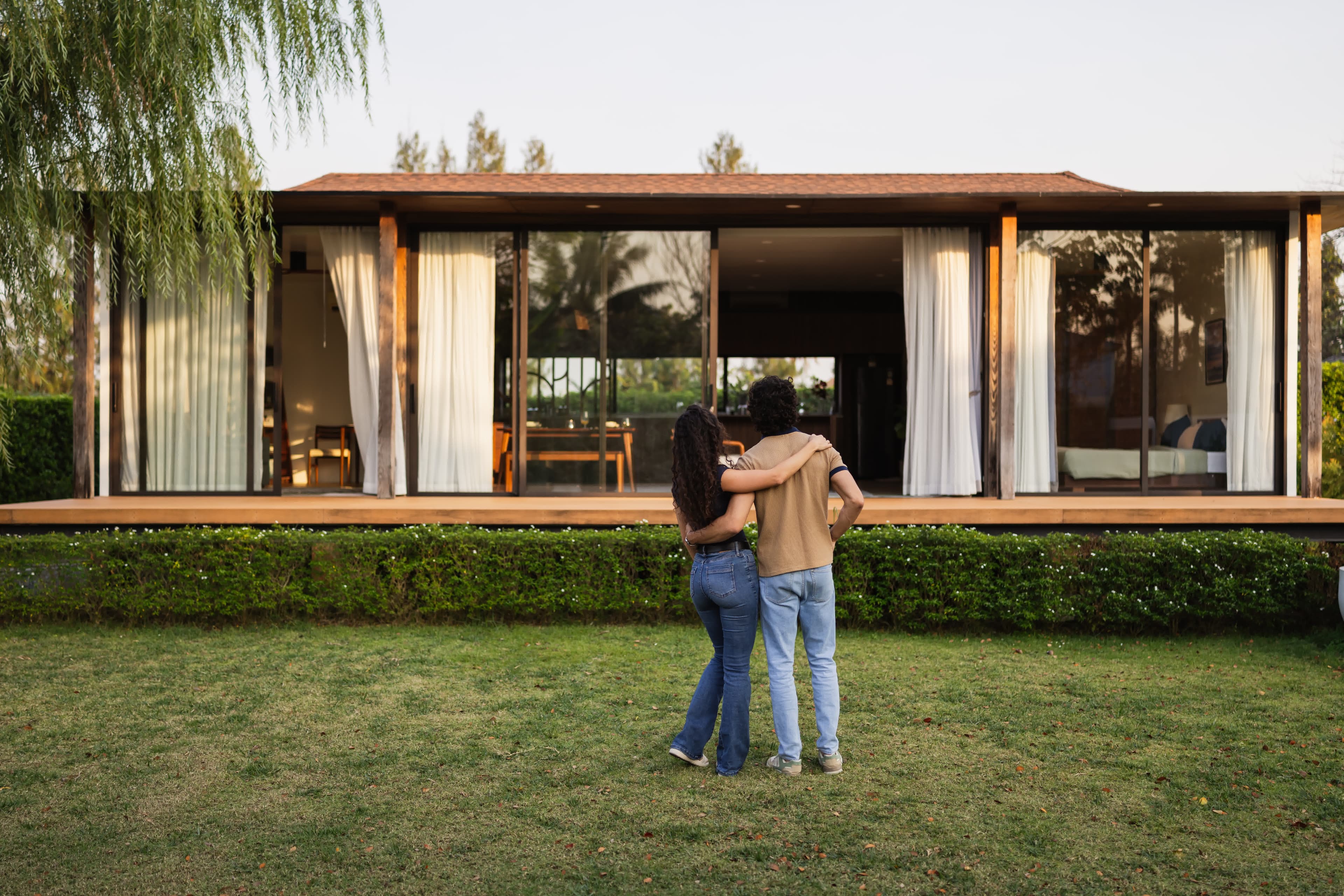 A high-net-worth couple admiring their modern luxury California home at dusk