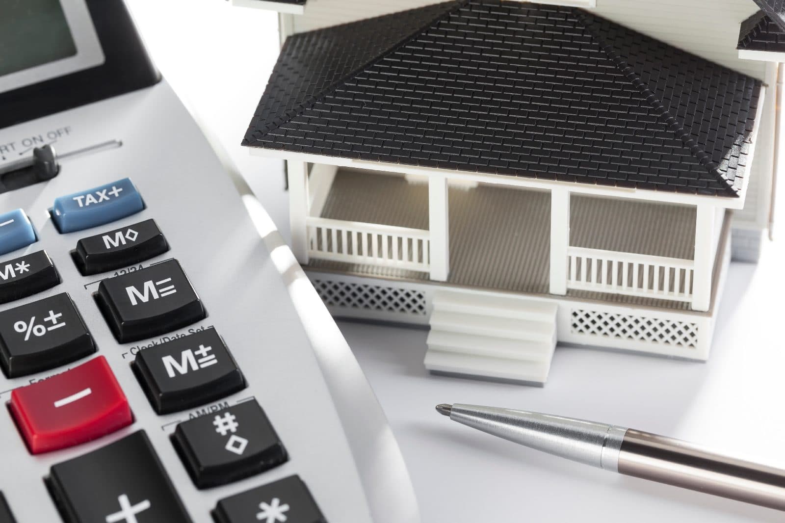 A calculator and model house illustrating the difference between rate and APR